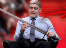 a man in a suit and tie is holding a large sword in his hands