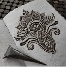 a drawing of a flower is on a piece of paper next to a henna cone