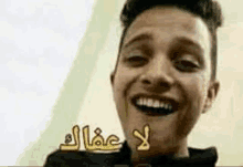 a young man with braces on his teeth is smiling with arabic writing on his face .