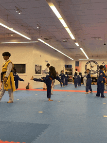 a group of kids are practicing martial arts in a gym with a sign that says karate