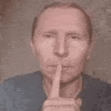 a man is holding his finger to his lips and making a silence sign .