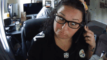 a woman wearing a pittsburgh steelers jersey talks on a cell phone