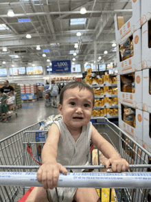 a baby sits in a shopping cart in front of a sign that says 1,000 on it