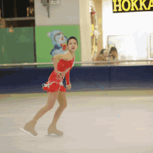 a woman in a red dress is skating on an ice rink in front of a sign that says hokka