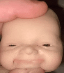 a close up of a baby doll 's face with a hand holding it