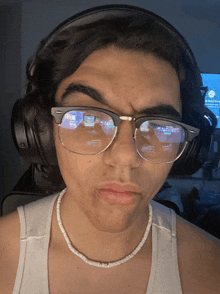 a man wearing glasses and headphones has a reflection of a computer screen in his glasses