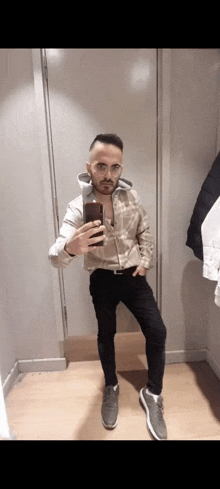 a man in a dressing room taking a selfie with his phone