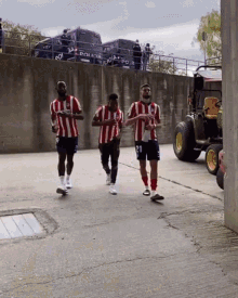 a group of soccer players are walking down a street in front of a wall that says policia on it