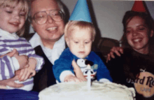 a little boy wearing a snoopy shirt is cutting a cake