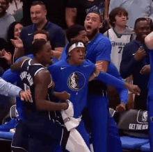 a group of basketball players are fighting each other in front of a crowd during a game .