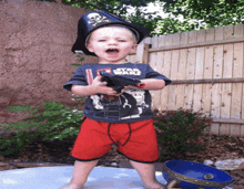 a young boy wearing a pirate hat and a star wars shirt holds a toy gun