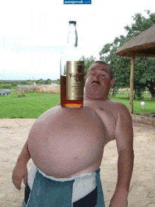 a man with a large belly is holding a bottle of veltins brandy