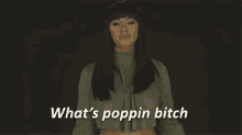 a woman is standing in front of a black background and says `` what 's poppin bitch ''