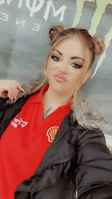 a woman wearing a red shell shirt and a black jacket takes a selfie