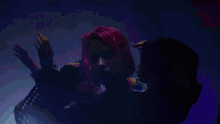 a woman with pink hair is dancing with another woman in a dark room