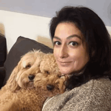 a woman is sitting on a couch with two small dogs .