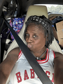 a woman in a car wearing a baby jersey makes a funny face