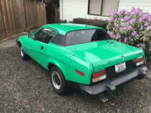 a green car with a license plate that says 36980 is parked in front of a house