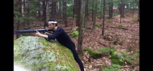 a man with a bandana on his head is holding a rifle in the woods