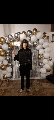 a man stands in front of a balloon arch holding a sign that says " jesus is my daddy "