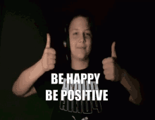 a boy wearing headphones gives two thumbs up with the words be happy be positive behind him