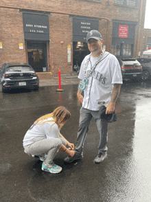 a man in a seahawks jersey is helping a little girl tie her shoe