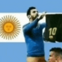 a man in a blue shirt is standing in front of an argentina flag and holding a black shirt with the number 10 on it .