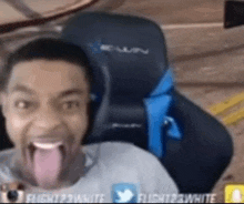 a man is sticking out his tongue while sitting in a chair .