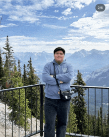 a man wearing a gap hoodie stands in front of mountains