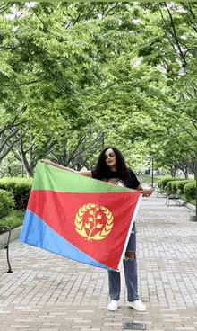 a woman is holding a flag in a park