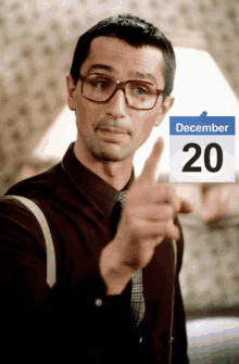 a man is pointing at a calendar that says december 20 on it