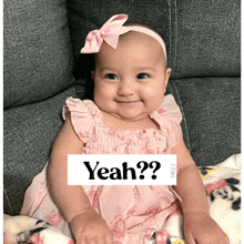 a baby is sitting on a couch with a sign that says " yeah "