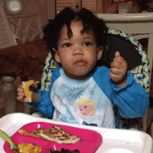 a little boy in a frozen shirt is giving a thumbs up