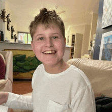 a young boy is smiling while sitting on a couch .