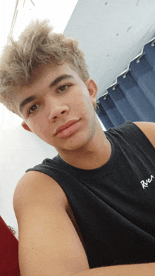 a young man taking a selfie with a river tank top on