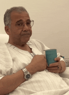 a man in a hospital gown is holding a cup