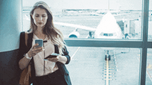 a woman leans against a wall looking at her cell phone