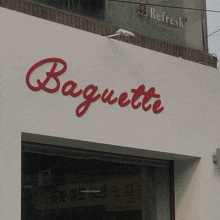 a white building with a red sign that reads baguette