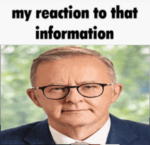 a man wearing glasses and a suit has the words my reaction to that information above his face