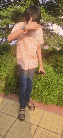 a boy covering his face with his hand while wearing a watch