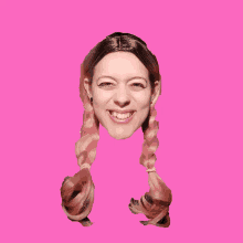 a woman with pigtails on a pink background smiles for the camera