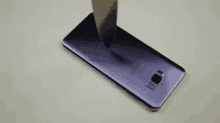 a purple cell phone is being smashed by a knife on a table .