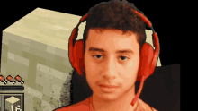 a young man wearing red headphones stands in front of a minecraft block