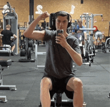 a man wearing headphones takes a selfie in a gym with the letter s on the wall