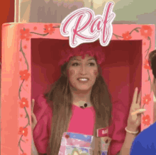 a woman in a pink dress is standing in a pink box with the word raf on it