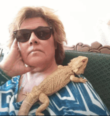 a woman with a lizard on her shoulder wearing sunglasses