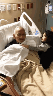 a little girl hugging an older man in a hospital bed with the word hop on the wall behind them