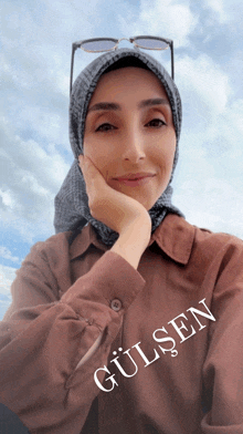 a woman wearing a head scarf and sunglasses has the name gülsen written on her shirt