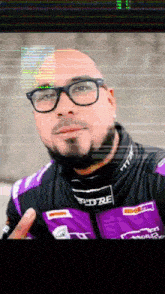 a man with a beard wearing glasses and a purple jacket that says pitbe on it