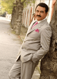 a man in a suit and tie leaning against a tree